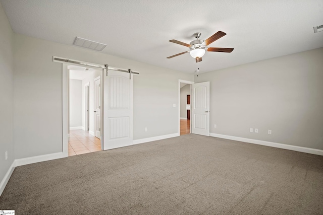 157 Deyoung Meadows Dr, Greer, SC 29651 - unfurnished bedroom with carpet flooring, a barn door, baseboards, a ceiling fan, and tile patterned flooring