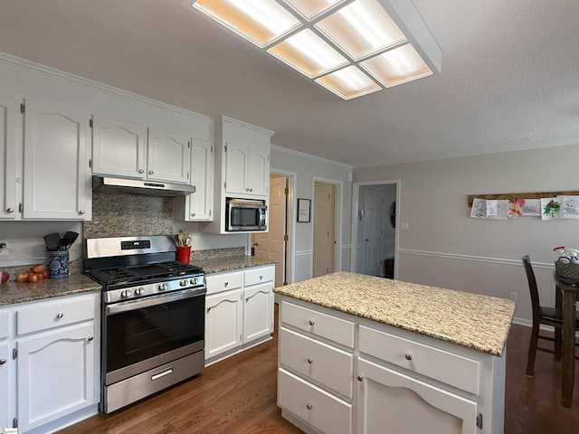 111 Firethorne Ct, Greer, SC 29650 - kitchen with appliances with stainless steel finishes, under cabinet range hood, white cabinetry, dark wood finished floors, and crown molding