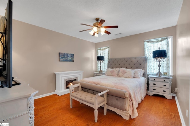 532 Cardinal Woods Way, Easley, SC 29642 - bedroom featuring baseboards, light wood finished floors, a warm lit fireplace, and a ceiling fan
