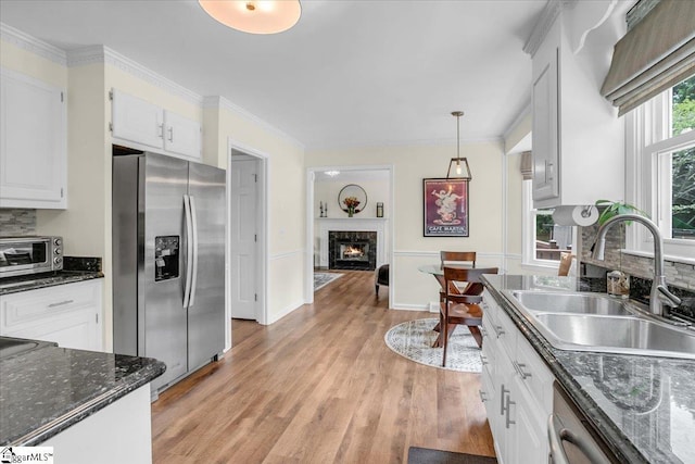 16 Chariot Ln, Simpsonville, SC 29681 - kitchen with stainless steel appliances, a sink, a lit fireplace, light wood-type flooring, and white cabinets