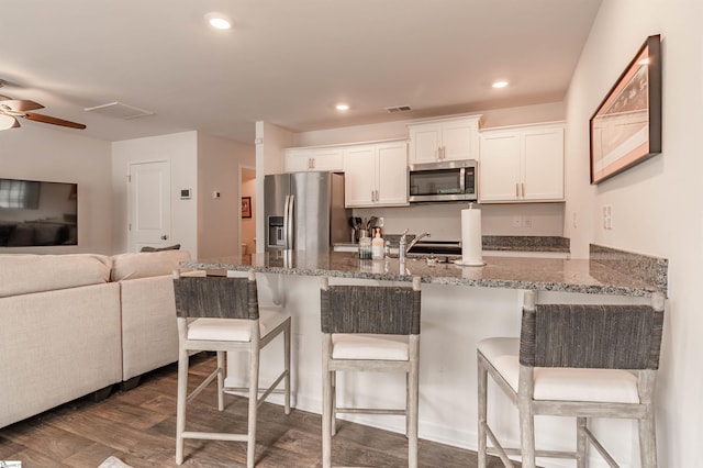 304 Oakmont Valley Trl, Seneca, SC 29678 - kitchen featuring stainless steel appliances, a kitchen bar, white cabinetry, stone counters, and dark wood-style floors