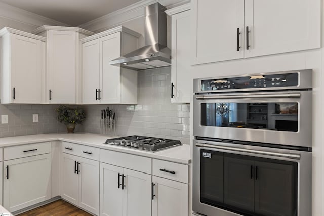 712 Paxton Rose Dr, Greer, SC 29650 - kitchen featuring wall chimney range hood, stainless steel appliances, white cabinetry, light countertops, and ornamental molding