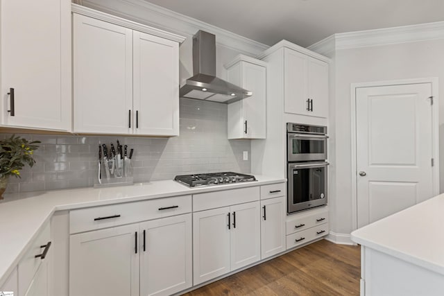 712 Paxton Rose Dr, Greer, SC 29650 - kitchen featuring wall chimney range hood, appliances with stainless steel finishes, ornamental molding, white cabinets, and wood finished floors