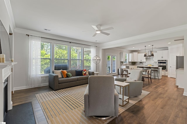 712 Paxton Rose Dr, Greer, SC 29650 - living room featuring ceiling fan, ornamental molding, a fireplace with flush hearth, dark wood-style floors, and baseboards