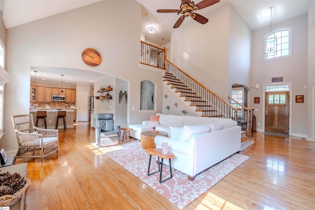 9 Windswept Knoll Dr, Taylors, SC 29687 - living room with arched walkways, a towering ceiling, a ceiling fan, stairs, and light wood-style floors