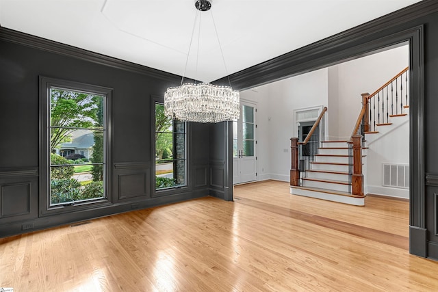 601 Brixton Cir, Simpsonville, SC 29681 - unfurnished dining area with a chandelier, stairway, light wood-style flooring, a decorative wall, and ornamental molding