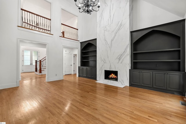 601 Brixton Cir, Simpsonville, SC 29681 - unfurnished living room featuring built in shelves, baseboards, light wood-style floors, a chandelier, and a high end fireplace