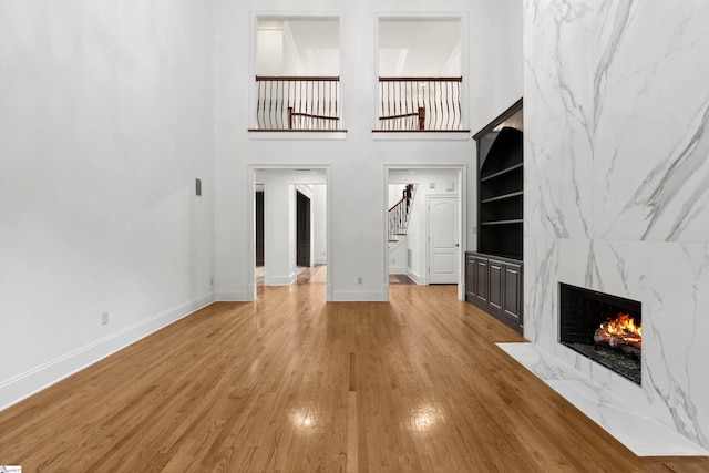 601 Brixton Cir, Simpsonville, SC 29681 - unfurnished living room with baseboards, stairway, a premium fireplace, light wood-style floors, and a high ceiling