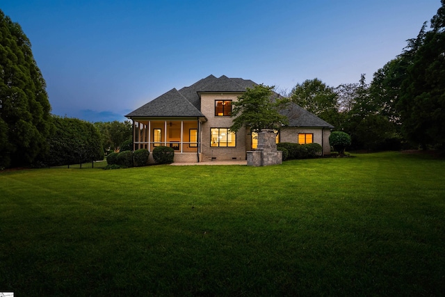 601 Brixton Cir, Simpsonville, SC 29681 - back of house at dusk featuring a sunroom, a lawn, crawl space, brick siding, and a shingled roof