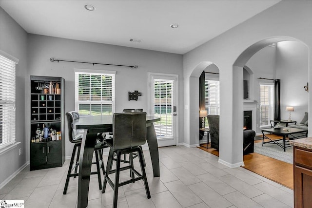 102 Eagle Pass Dr, Taylors, SC 29687 - dining space featuring a lit fireplace, arched walkways, recessed lighting, light tile patterned floors, and baseboards