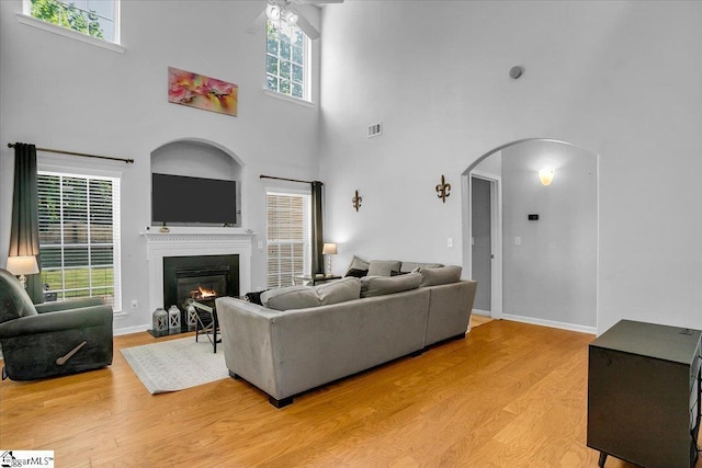 102 Eagle Pass Dr, Taylors, SC 29687 - living area with arched walkways, a towering ceiling, ceiling fan, a glass covered fireplace, and light wood-style floors