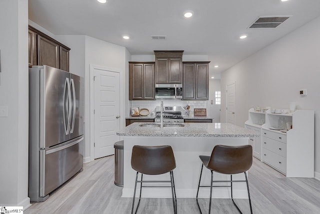 404 Hillrock Ct, Greenville, SC 29617 - kitchen with stainless steel appliances, a sink, dark brown cabinets, light wood-type flooring, and an island with sink