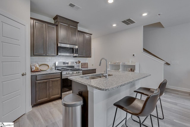 404 Hillrock Ct, Greenville, SC 29617 - kitchen featuring appliances with stainless steel finishes, a sink, light wood-style floors, a center island with sink, and decorative backsplash