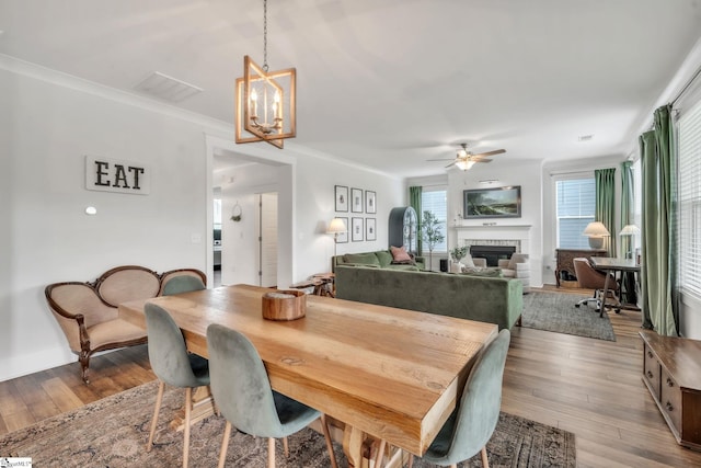 706 Torridon Ln, Simpsonville, SC 29681 - dining space with a fireplace, ceiling fan, light wood-style flooring, a chandelier, and ornamental molding