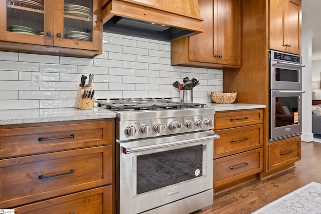 100 Sunrise Valley Rd, Greenville, SC 29617 - kitchen with appliances with stainless steel finishes, brown cabinets, dark wood-type flooring, glass insert cabinets, and tasteful backsplash
