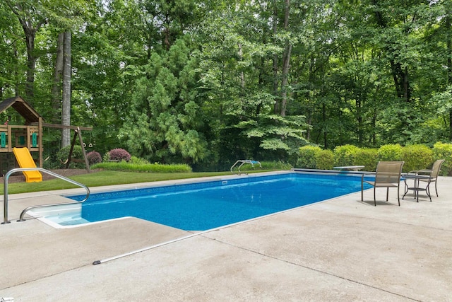 119 Oak Crest Cir, Seneca, SC 29672 - swimming pool featuring a patio area, a playground, a diving board, and view of wooded area
