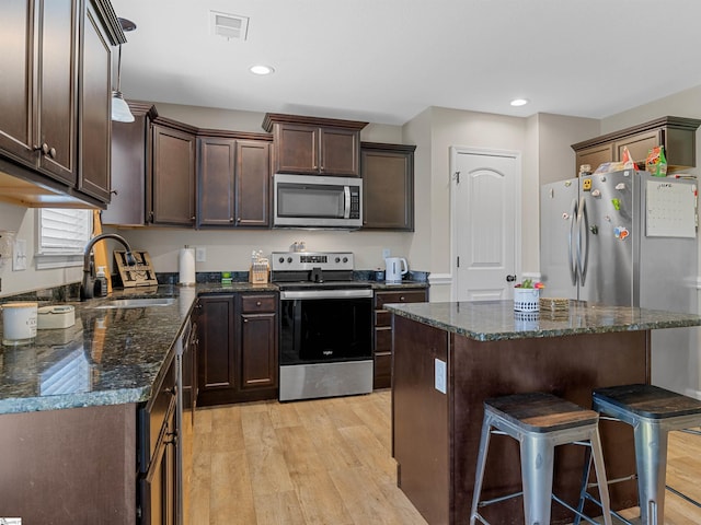 825 Brennan Way, Lyman, SC 29365 - kitchen with appliances with stainless steel finishes, a sink, dark brown cabinetry, a breakfast bar area, and light wood finished floors