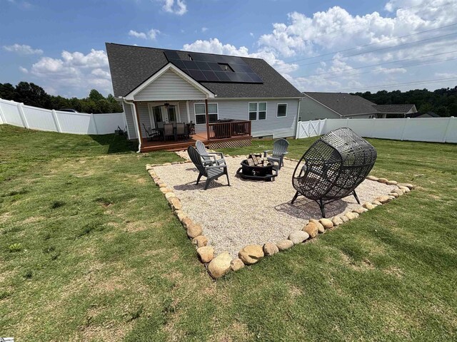 844 Brennan Way, Lyman, SC 29365 - back of property featuring an outdoor fire pit, a wooden deck, roof mounted solar panels, and a shingled roof