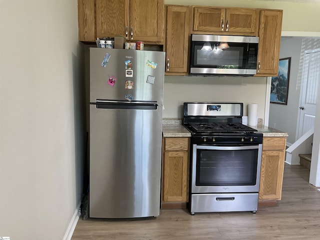407 Old Farm Rd, Moore, SC 29539 - kitchen with stainless steel appliances, light wood-style flooring, brown cabinetry, and baseboards