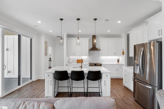 110 Chicken Foot Creek Rd, Woodruff, SC 29388 - kitchen with stainless steel appliances, wall chimney range hood, light countertops, tasteful backsplash, and wood finished floors