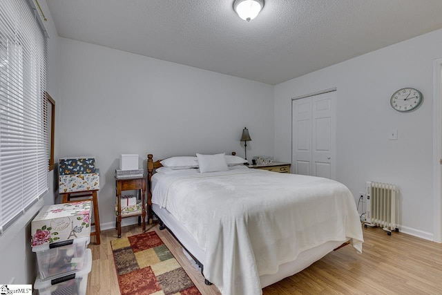 710 Amy Gray St, Greer, SC 29651 - bedroom featuring radiator heating unit, light wood finished floors, a closet, baseboards, and a textured ceiling