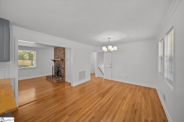 304 Robin Hood Rd, Greenville, SC 29607 - unfurnished living room with light wood-style floors, a chandelier, baseboards, crown molding, and a brick fireplace