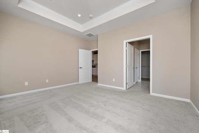6010 Ives Ave, Spartanburg, SC 29307 - unfurnished bedroom featuring ornamental molding, a raised ceiling, light colored carpet, baseboards, and a walk in closet