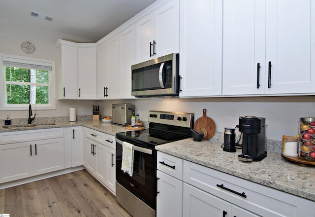 1608 Rock Springs Rd, Lavonia, GA 30553 - kitchen featuring appliances with stainless steel finishes, a sink, white cabinets, and light wood-style floors