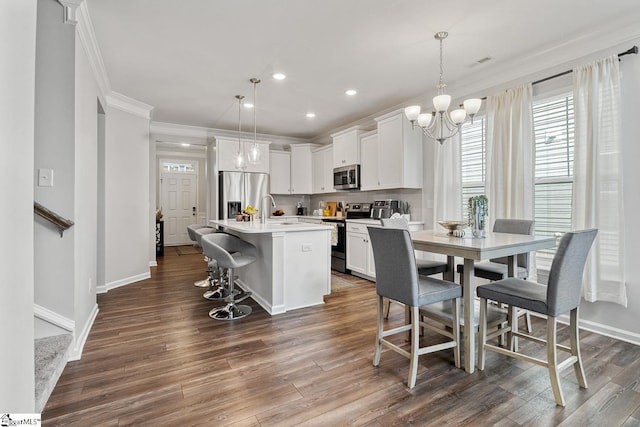 106 Cross Arbor Dr, Simpsonville, SC 29681 - kitchen featuring stainless steel appliances, ornamental molding, healthy amount of natural light, dark wood-style floors, and a center island with sink