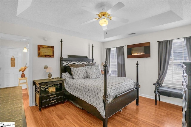 104 Pin Oak Dr, Greenwood, SC 29649 - bedroom with a raised ceiling, light wood-style floors, a textured ceiling, baseboards, and ceiling fan