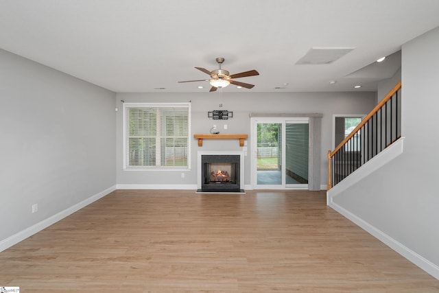 100 Holly Dr, Duncan, SC 29334 - unfurnished living room featuring baseboards, light wood-style floors, ceiling fan, a warm lit fireplace, and stairs