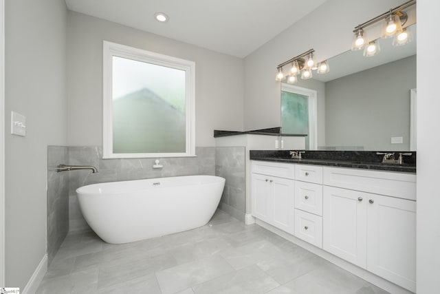 100 Holly Dr, Duncan, SC 29334 - full bathroom featuring double vanity, a freestanding tub, tile walls, a wainscoted wall, and marble look tiles