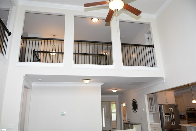 127 Riverland Woods Ct, Simpsonville, SC 29681 - detailed view of stainless steel refrigerator with ice dispenser, crown molding, ceiling fan, wall oven, and glass insert cabinets