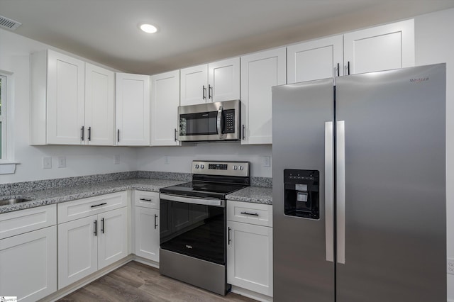 3834 Maid Marion Ln, Spartanburg, SC 29302 - kitchen featuring appliances with stainless steel finishes, white cabinets, wood finished floors, recessed lighting, and light stone countertops