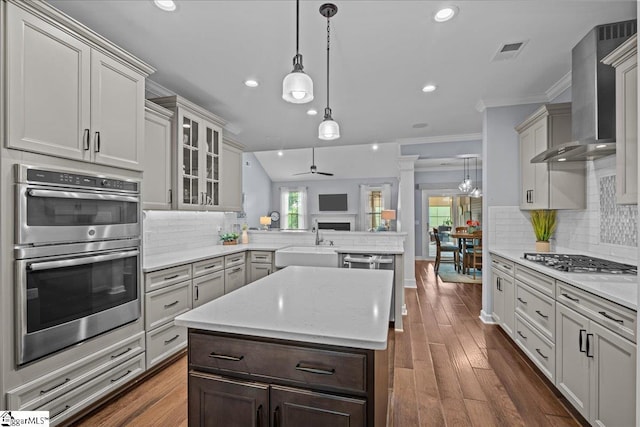 79 Modesto Ln, Simpsonville, SC 29681 - kitchen featuring appliances with stainless steel finishes, a peninsula, a sink, wall chimney range hood, and ornamental molding