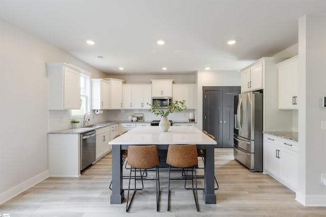 738 Judah Dr, Moore, SC 29369 - kitchen featuring stainless steel appliances, a breakfast bar area, white cabinetry, a center island, and light wood-type flooring