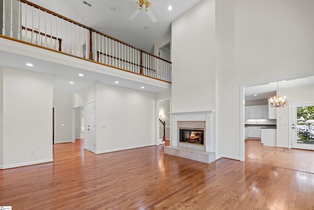 118 Pinnacle Pointe Dr, Seneca, SC 29672 - unfurnished living room with a towering ceiling, a fireplace, a ceiling fan, light wood-type flooring, and a chandelier