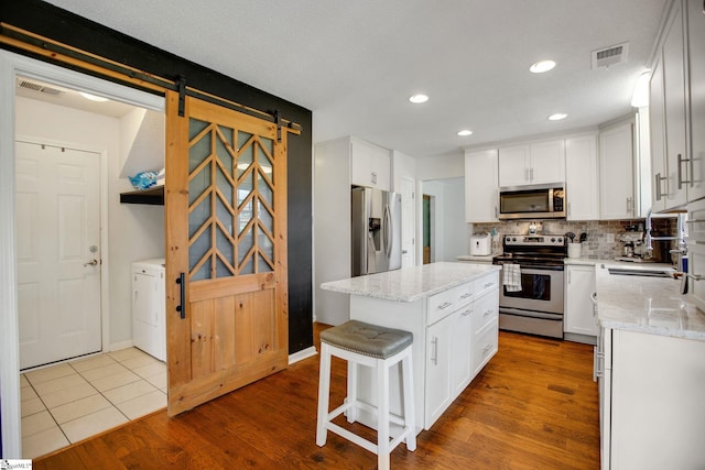101 Bitternut Ln, Taylors, SC 29687 - kitchen featuring appliances with stainless steel finishes, white cabinetry, a barn door, light stone counters, and recessed lighting