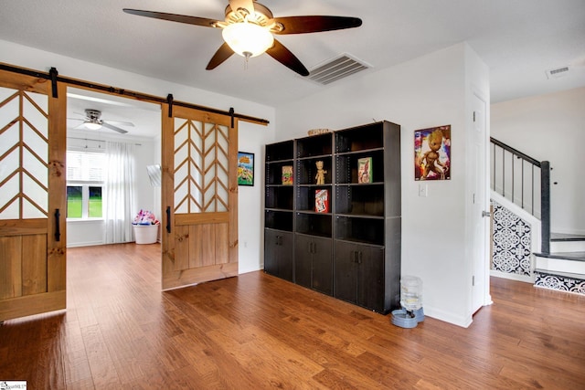 101 Bitternut Ln, Taylors, SC 29687 - spare room with a barn door, wood finished floors, a ceiling fan, and stairway