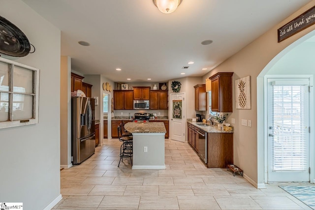 208 Castleton Cir, Boiling Springs, SC 29316 - kitchen with appliances with stainless steel finishes, arched walkways, a breakfast bar area, a center island, and light stone countertops