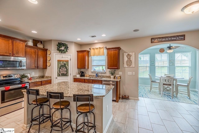 208 Castleton Cir, Boiling Springs, SC 29316 - kitchen with appliances with stainless steel finishes, a kitchen breakfast bar, light stone counters, brown cabinetry, and recessed lighting