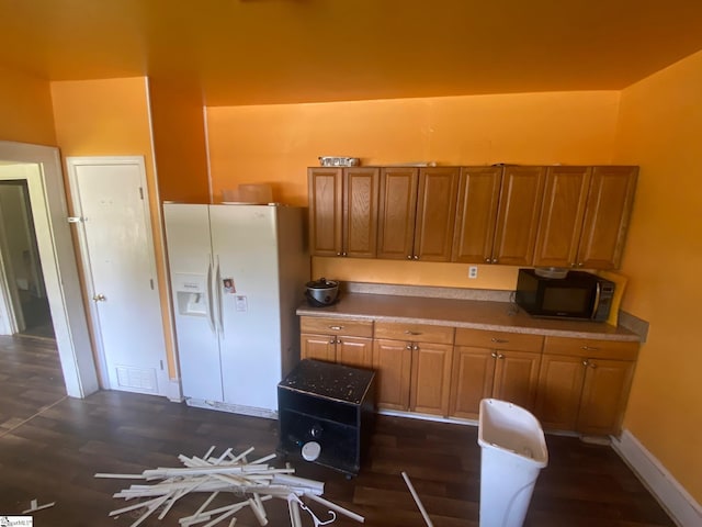 719 Chestnut St, Laurens, SC 29360 - kitchen with white refrigerator with ice dispenser, black microwave, brown cabinetry, and dark wood-type flooring