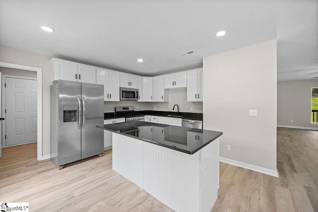 1016 Scott Rd, Anderson, SC 29621 - kitchen featuring stainless steel appliances, white cabinetry, light wood-style flooring, dark countertops, and a center island