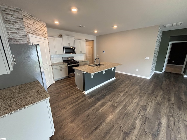 63 Oak Edge Ln, Greer, SC 29651 - kitchen featuring stainless steel appliances, dark wood-type flooring, a kitchen island with sink, white cabinets, and backsplash
