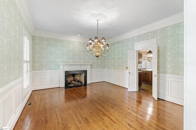 15 Annas Pl, Simpsonville, SC 29681 - unfurnished living room with a chandelier, wallpapered walls, a wainscoted wall, wood finished floors, and a premium fireplace