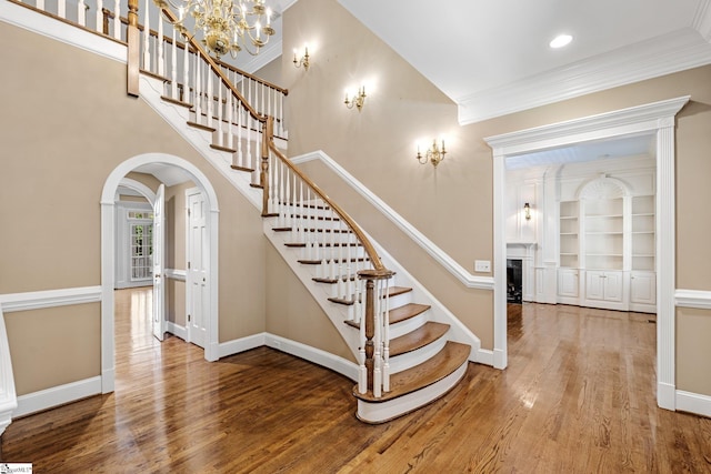 15 Annas Pl, Simpsonville, SC 29681 - stairs with wood finished floors, crown molding, arched walkways, a fireplace, and a chandelier