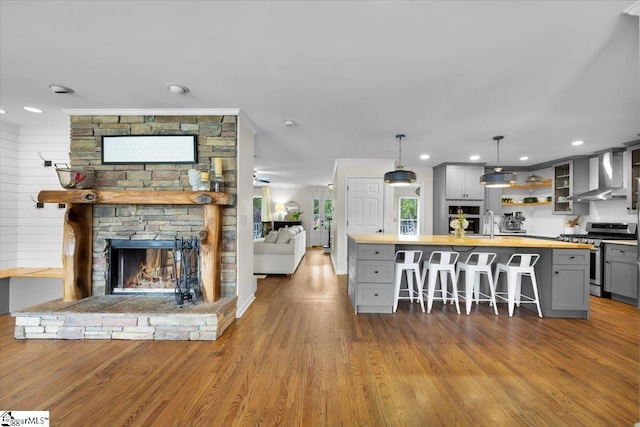 109 W Fieldsparrow Cir, Greenville, SC 29615 - kitchen featuring stainless steel gas range oven, wall chimney range hood, gray cabinetry, open floor plan, and a breakfast bar area