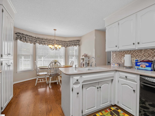 209 Thornhill Dr, Spartanburg, SC 29301 - kitchen featuring a peninsula, wood finished floors, white cabinets, a chandelier, and a textured ceiling