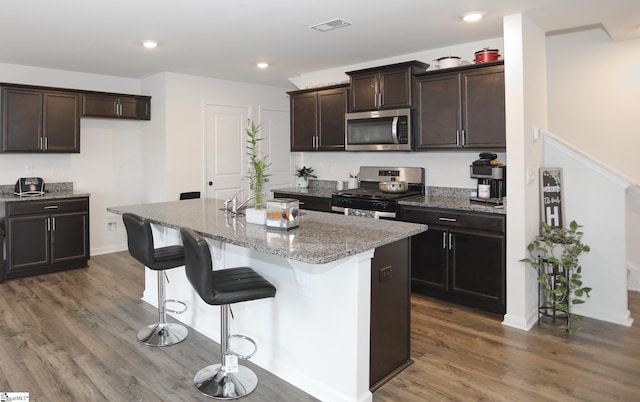 1421 Trotting Ave, Roebuck, SC 29376 - kitchen with stainless steel appliances, dark wood finished floors, light stone counters, a kitchen island with sink, and recessed lighting