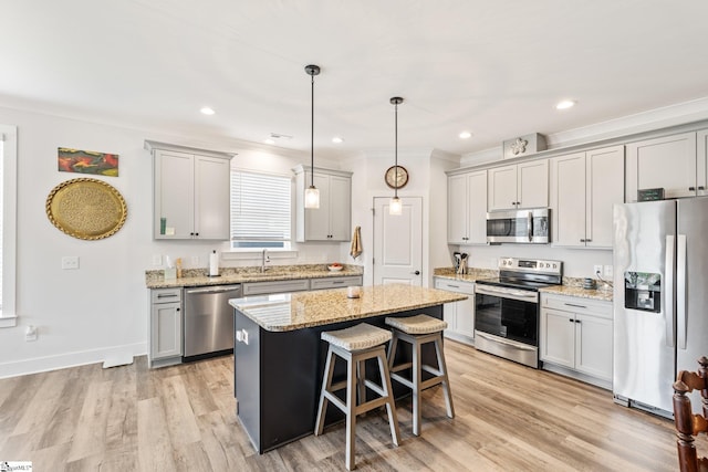 27 Mossycup Rd, Taylors, SC 29687 - kitchen with appliances with stainless steel finishes, a center island, a breakfast bar area, light wood-style floors, and light stone counters